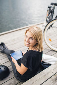 Portrait of smiling businesswoman using digital tablet while sitting on steps