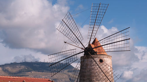 Low angle view of traditional windmill against cloudy sky