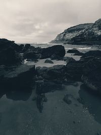 Reflection of rocks in sea against sky