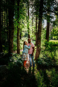 Biracial couple standing and laughing in forest