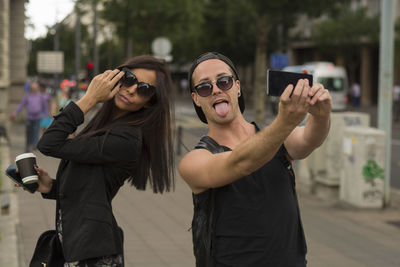 Young couple taking selfie on street through mobile phone