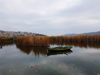 Boat floating on lake against sky