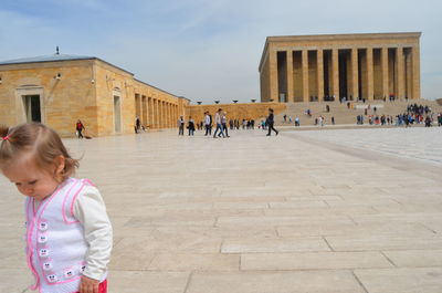 Girl standing against historic building