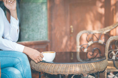 Midsection of woman with coffee on table 