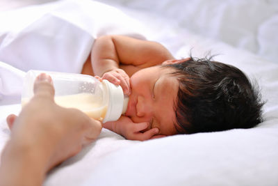 Cropped image of mother feeding milk to newborn