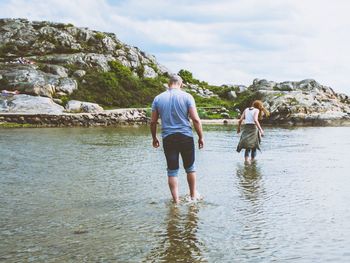 Rear view of couple walking through shallow water