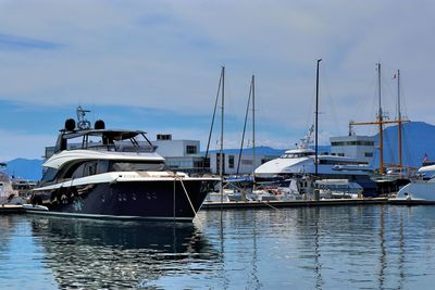 Sailboats moored at harbor against sky