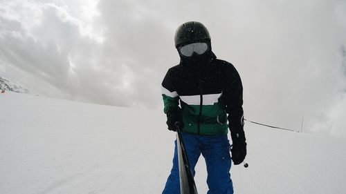 Man in warm clothing holding monopod while standing on snow