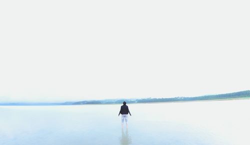 Rear view of man overlooking calm sea