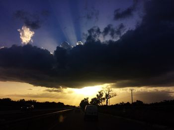 Silhouette road against dramatic sky during sunset