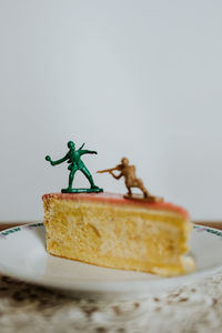 Two toy soldiers fighting on the top of a piece of cake about calories - close up white background