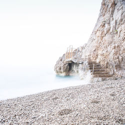 Rocks in sea against clear sky