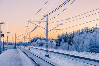 Snow covered railroad tracks against sky during winter