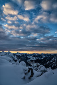 Snow covered landscape against sky during sunset