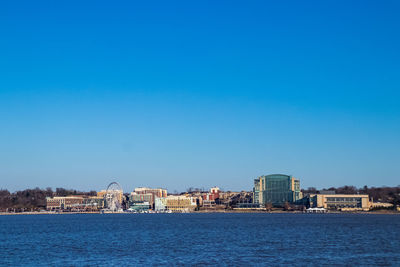 Sea by buildings against clear blue sky