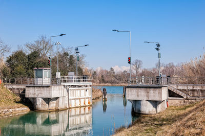 Built structure by river against clear blue sky