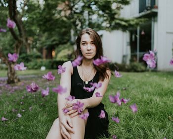 Flowers falling on woman sitting in grass