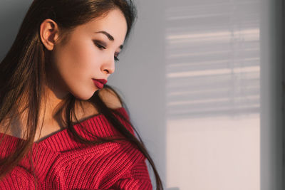 Close-up portrait of a young woman looking away at home