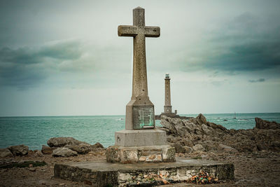 Cross by sea against sky