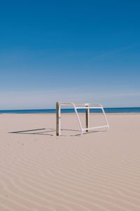 Deck chairs on beach against clear blue sky