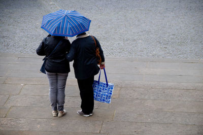 Rear view of women holding umbrella while standing on street
