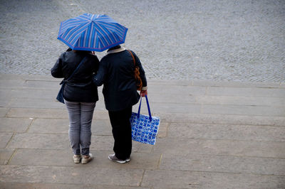 Rear view of woman walking with umbrella