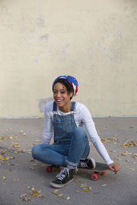 Portrait of smiling young woman sitting on wall