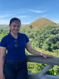 Portrait of smiling young woman standing on landscape