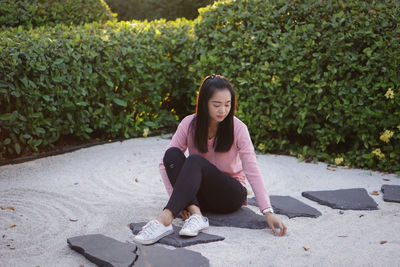 Portrait of young woman sitting on footpath
