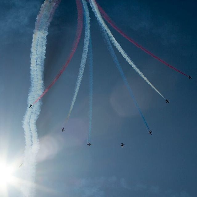 low angle view, flying, blue, sky, mid-air, vapor trail, air vehicle, airplane, transportation, cloud - sky, outdoors, travel, day, motion, no people, mode of transport, wind, clear sky, nature, flag