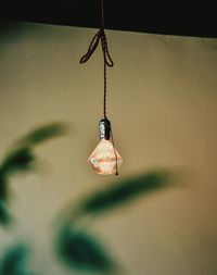 Close-up of light bulb hanging against wall