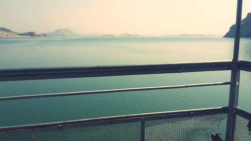 Close-up of railing by sea against clear sky