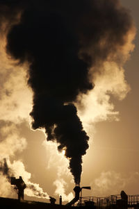 Smoke emitting from industrial pipe against sky at sunset