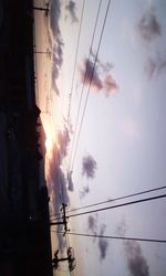 Low angle view of electricity pylon against sky during sunset