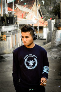 Young man listening music while standing on footpath