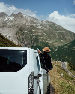 Man standing by car on mountain against sky