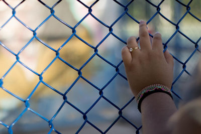 Cropped hand of woman on chainlink fence