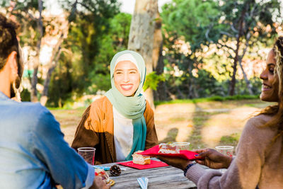 Smiling young woman enjoying food with friends