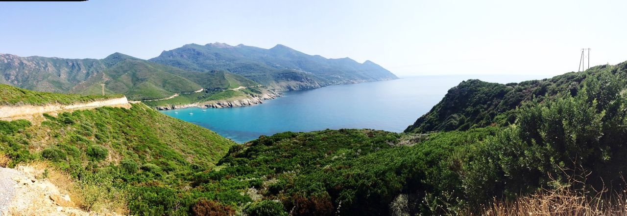 mountain, tranquil scene, water, tranquility, scenics, beauty in nature, clear sky, nature, mountain range, sea, landscape, sky, lake, idyllic, non-urban scene, grass, plant, remote, day, coastline