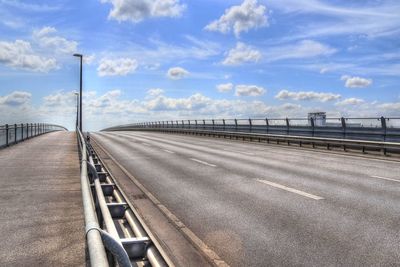 Road by bridge in city against sky