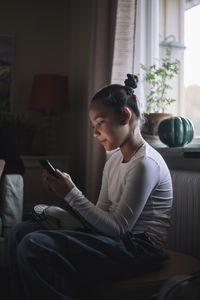 Girl using smart phone while sitting at home