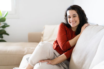 Young woman sitting on sofa at home