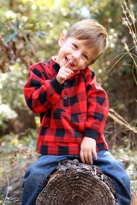 Portrait of cute boy sitting on tree stump