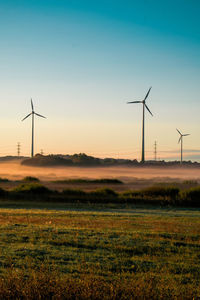 Windmills on field against clear sky