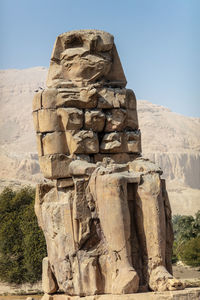 Beautiful daytime view of the colossi of memnon. two large stone figures depicting a seated pharaoh.