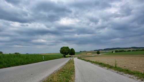 Road amidst field against sky