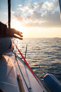 Sailboat sailing on sea against sky during sunset