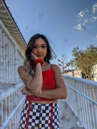 Portrait of young woman standing against railing