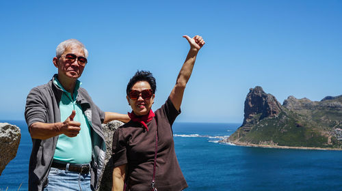 Portrait of happy friends by sea against clear sky