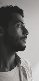 Close-up of thoughtful young man looking away against wall